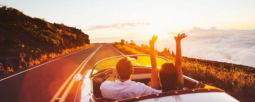 Happy Couple Driving on Country Road into the Sunset in Classic Happy Couple Driving on Country Road into the Sunset in Classic Vintage Sports Car