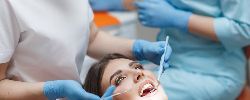 Dental clinic. Reception, examination of the patient. Teeth care. Young woman undergoes a dental examination by a dentist.Happy patient and dentist concept.Female dentist in dental office talking with girl patient.Beautiful teeth