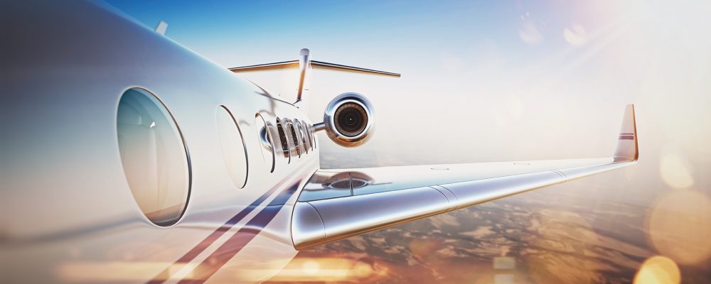 Business travel concept.Generic design of white luxury private jet flying in blue sky at sunset.Uninhabited desert mountains on the background.Horizontal, flares effect. 3D rendering.